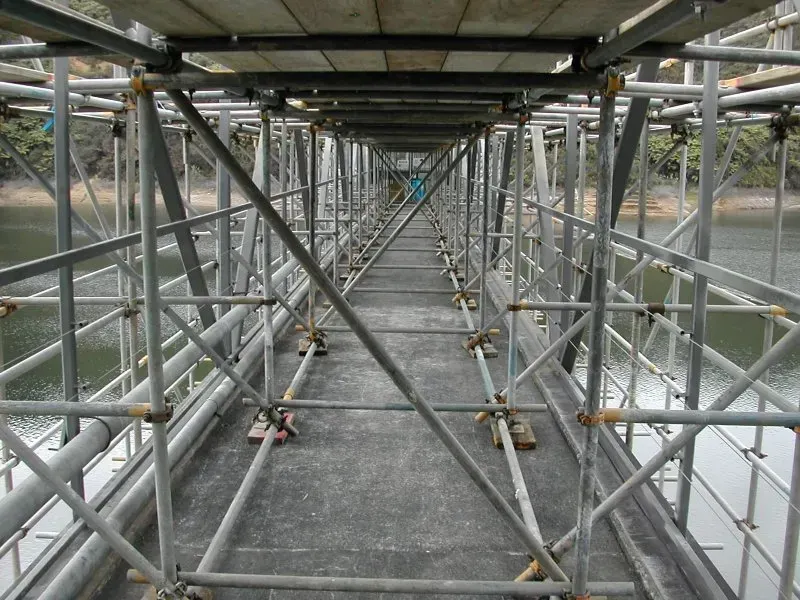 A bridge made of scaffolding is being built over a body of water