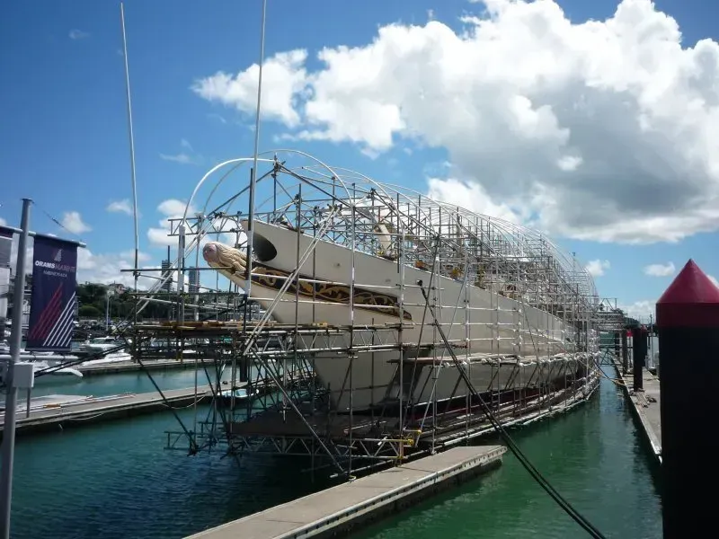 A boat is being built in a harbor with scaffolding around it