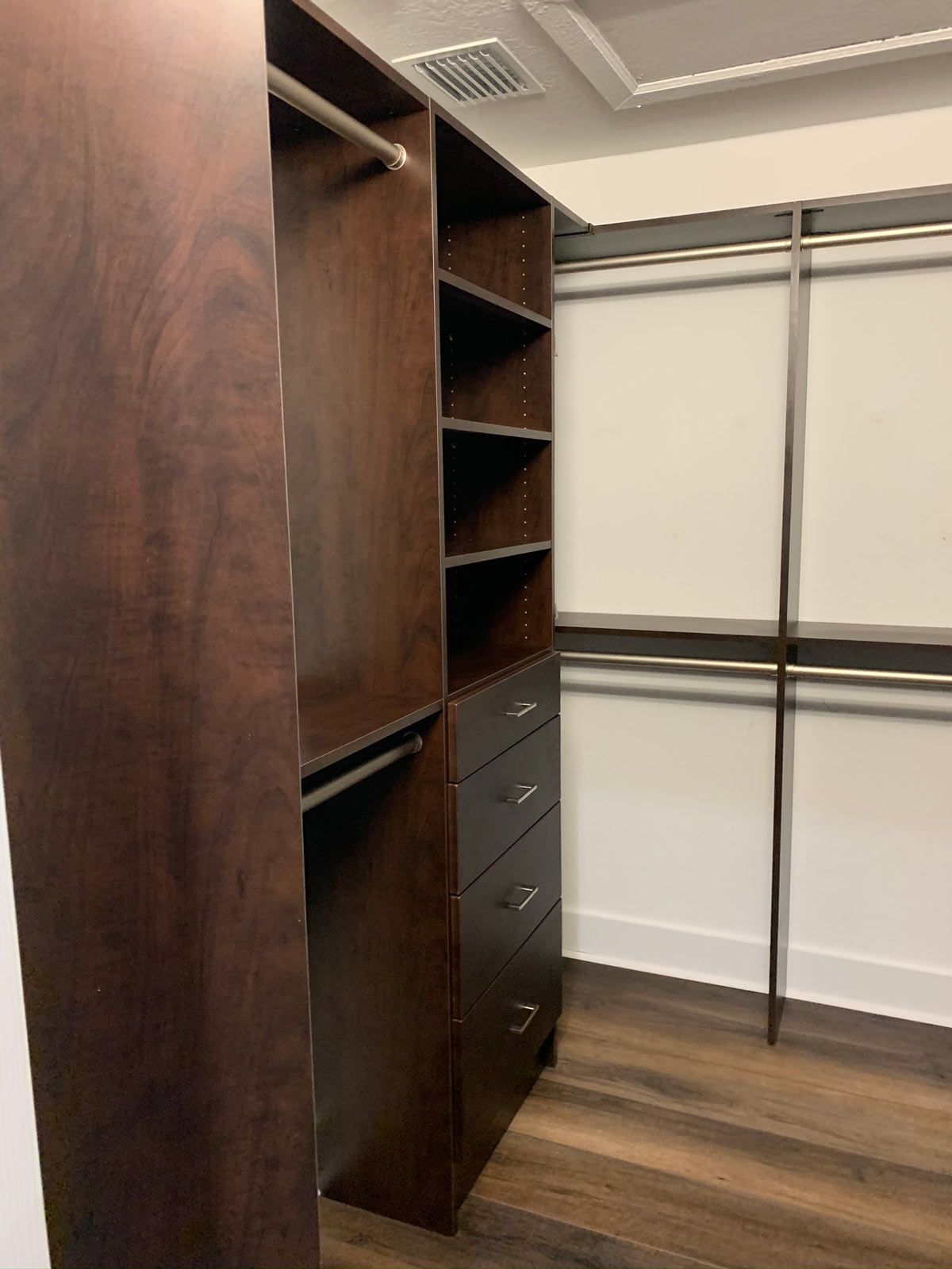 A walk in closet with wooden shelves and drawers.