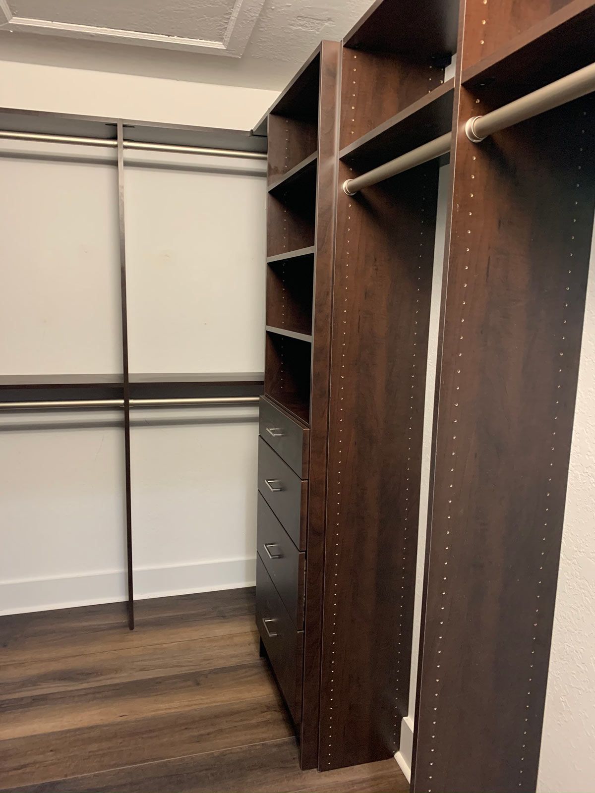 A walk in closet with wooden shelves and drawers.