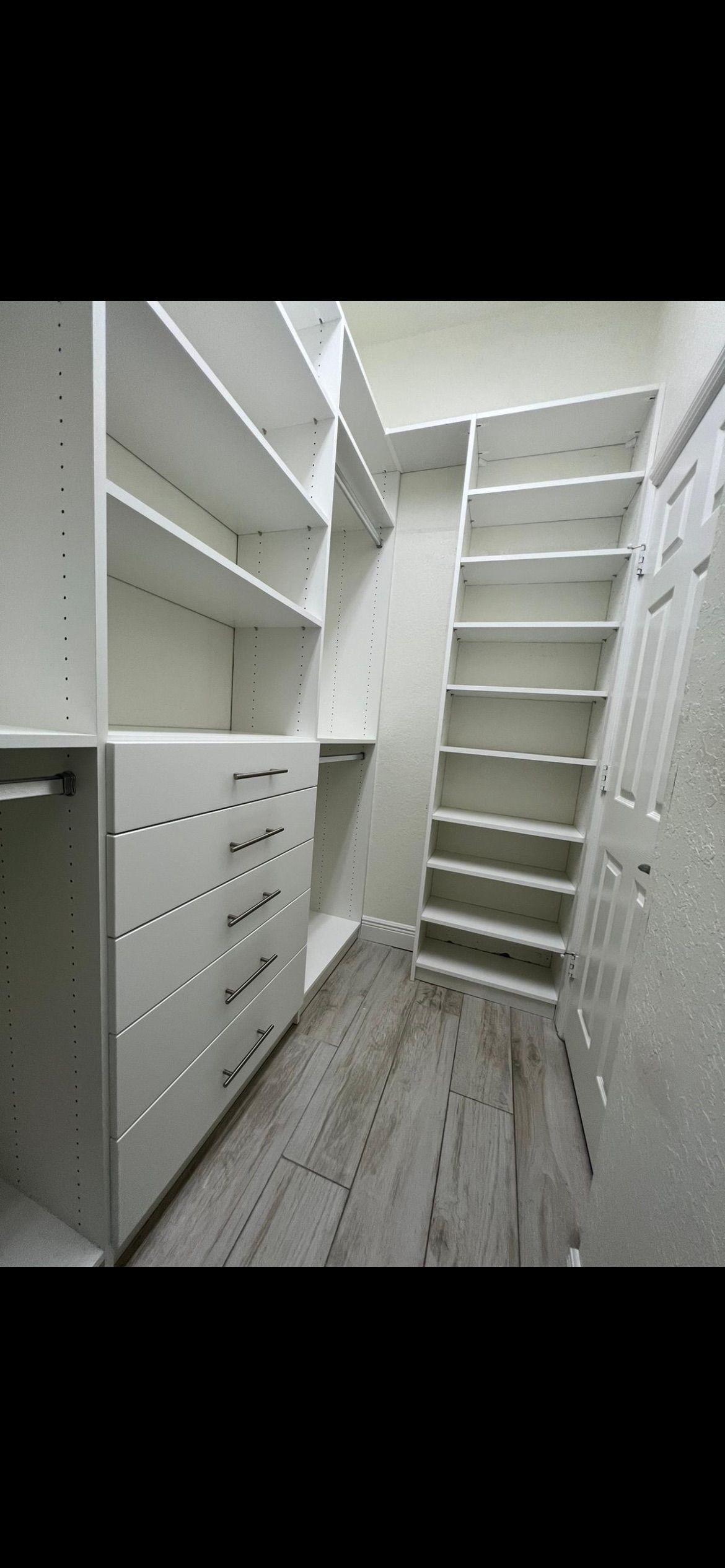 A walk in closet with lots of shelves and drawers.