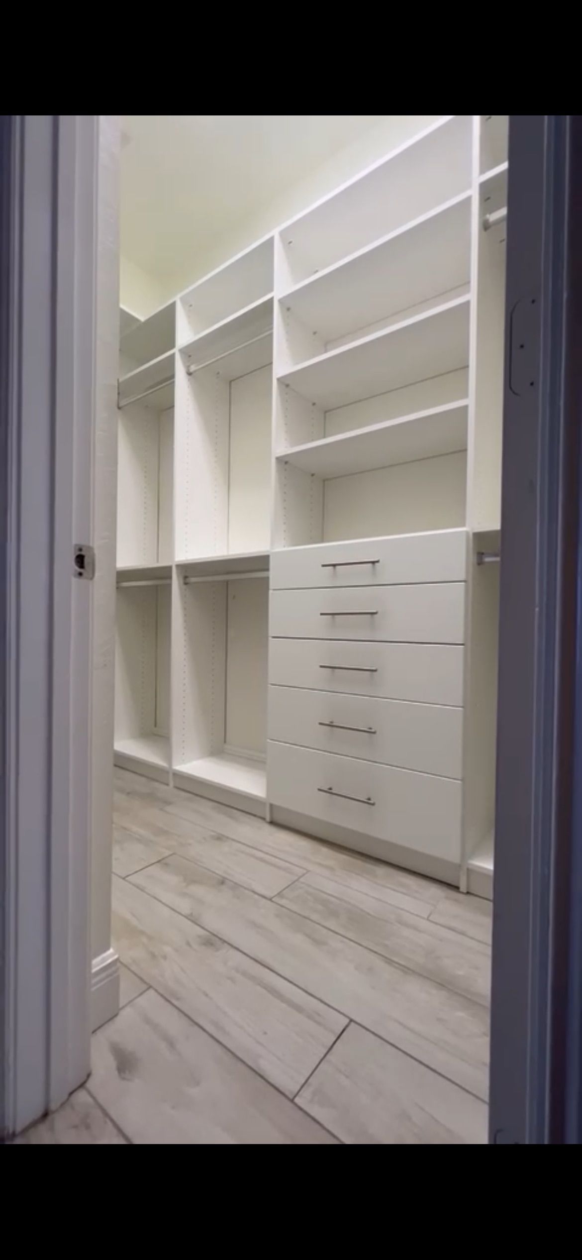 A walk in closet with lots of shelves and drawers.