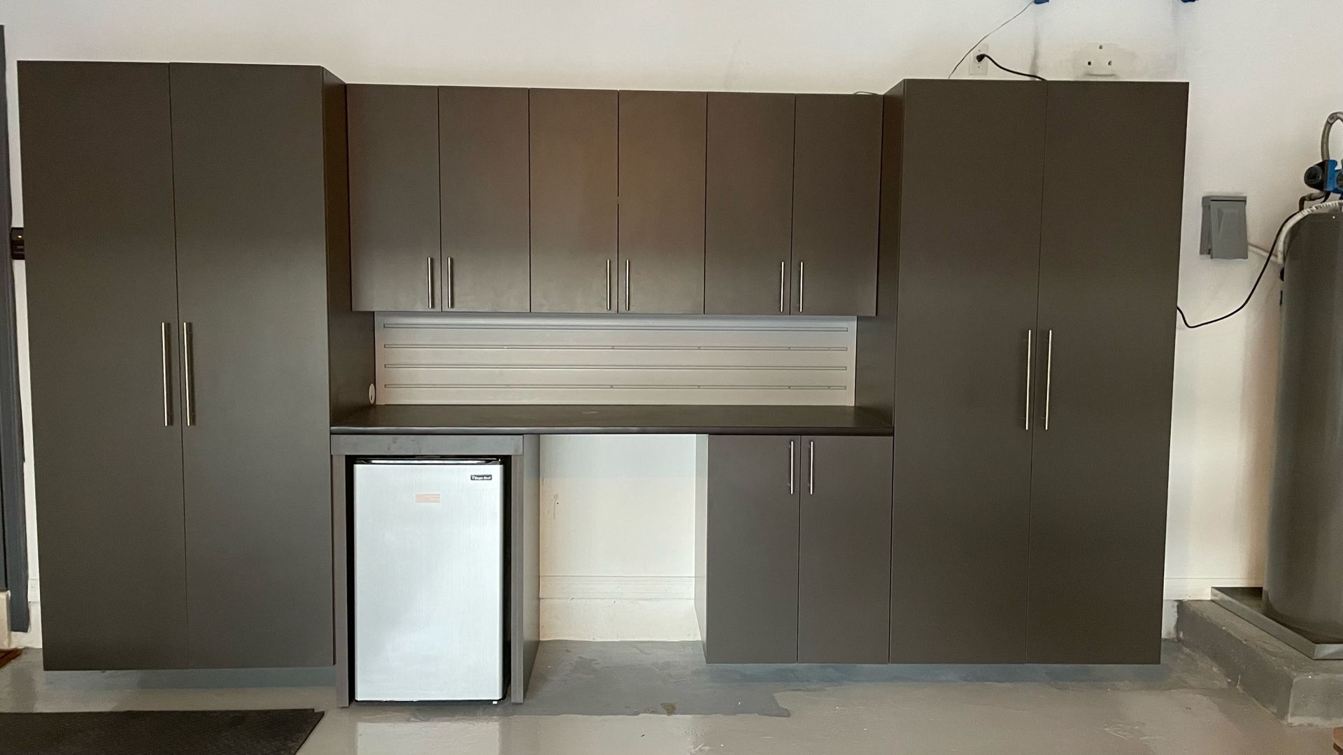 A garage with a lot of cabinets and a small refrigerator