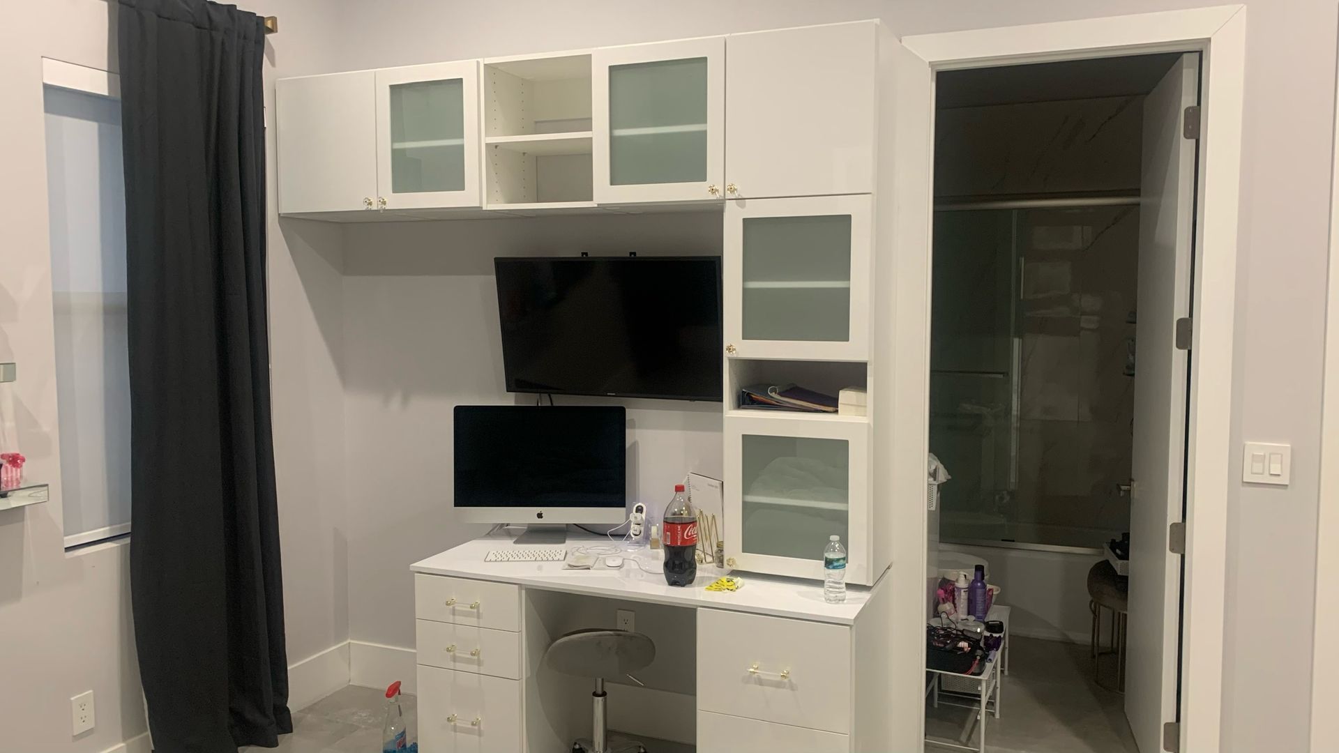 A room with a desk and a television on the wall.