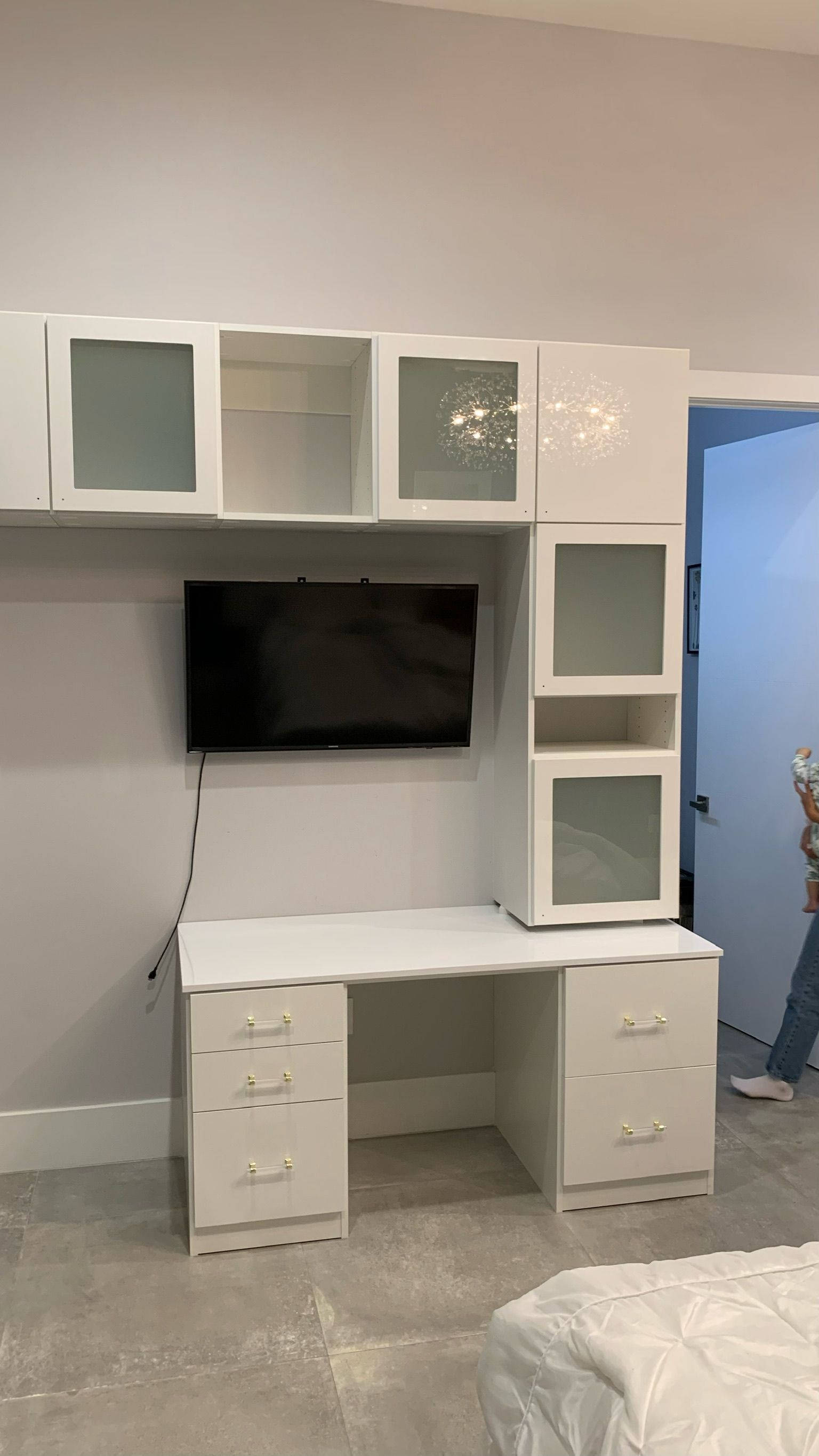 A bedroom with a desk and a television on the wall.
