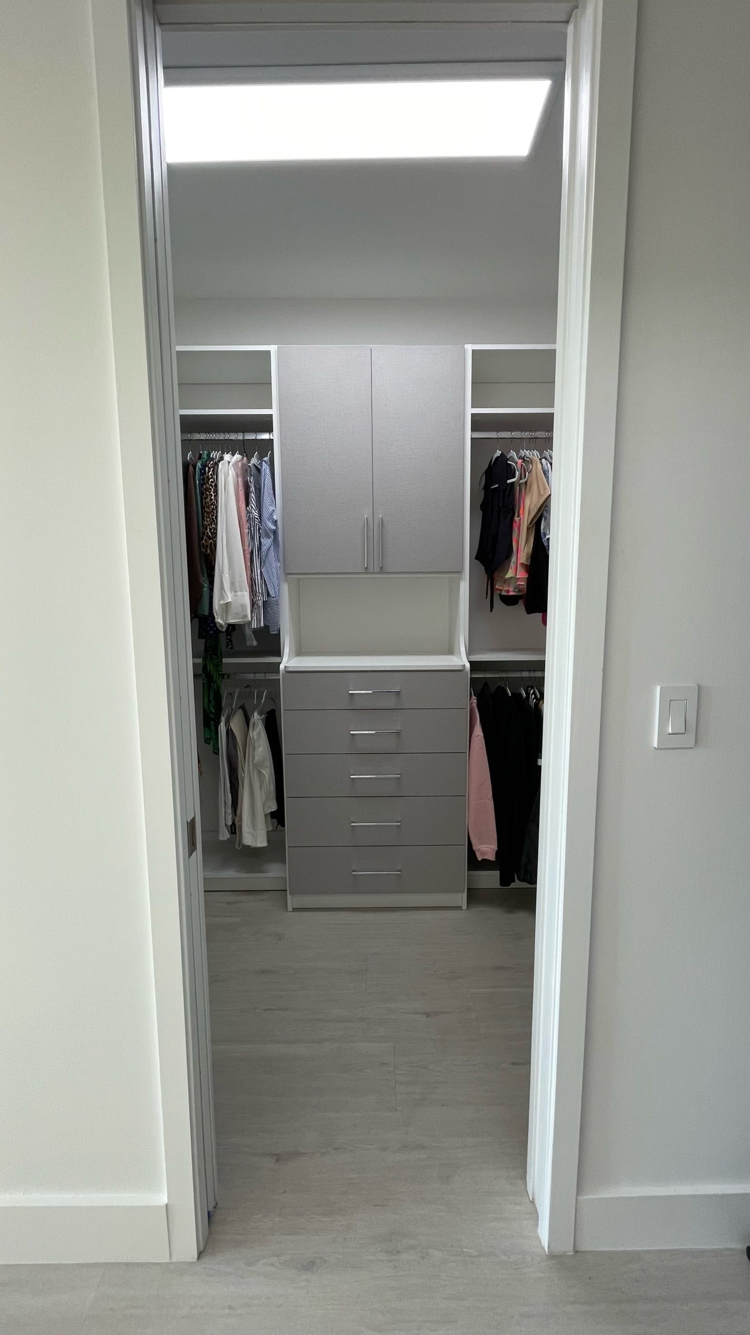 A walk in closet with lots of clothes in it.