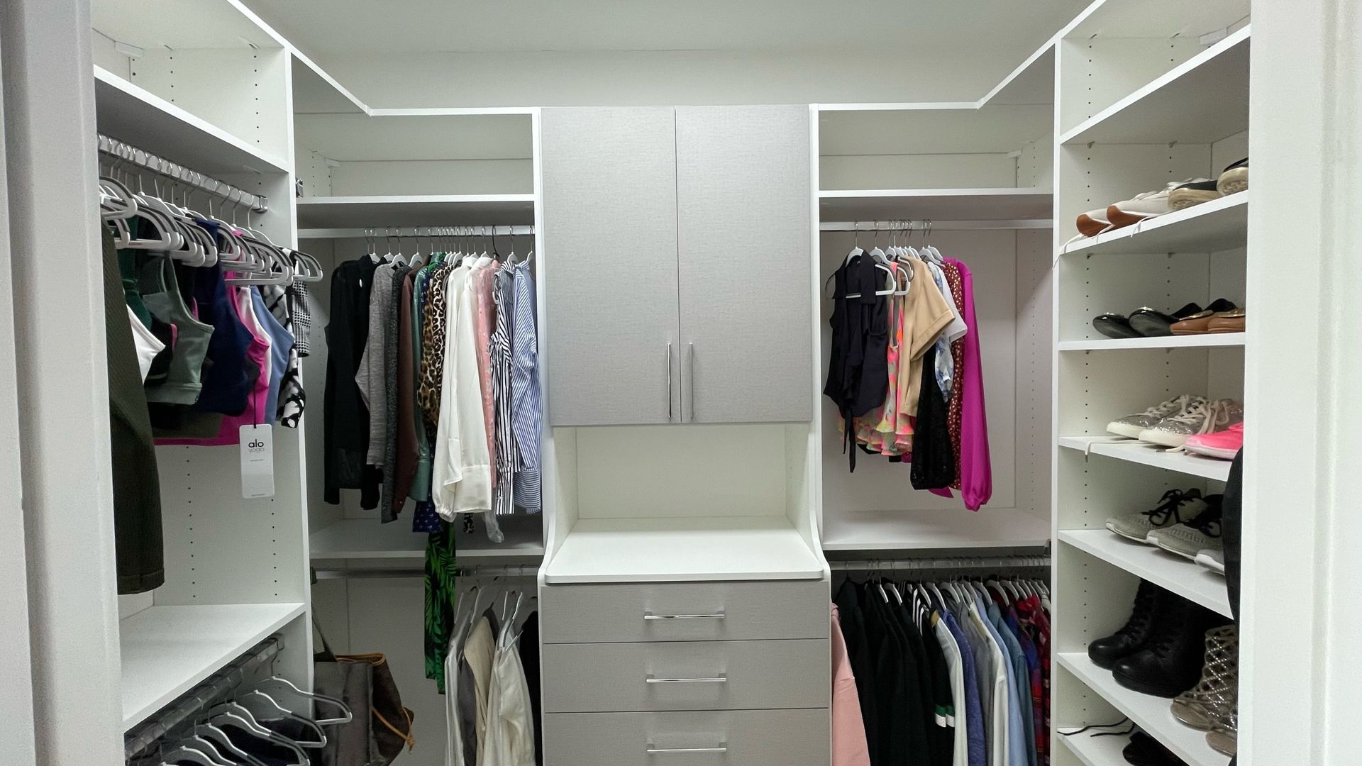 A walk in closet filled with lots of clothes and shoes.