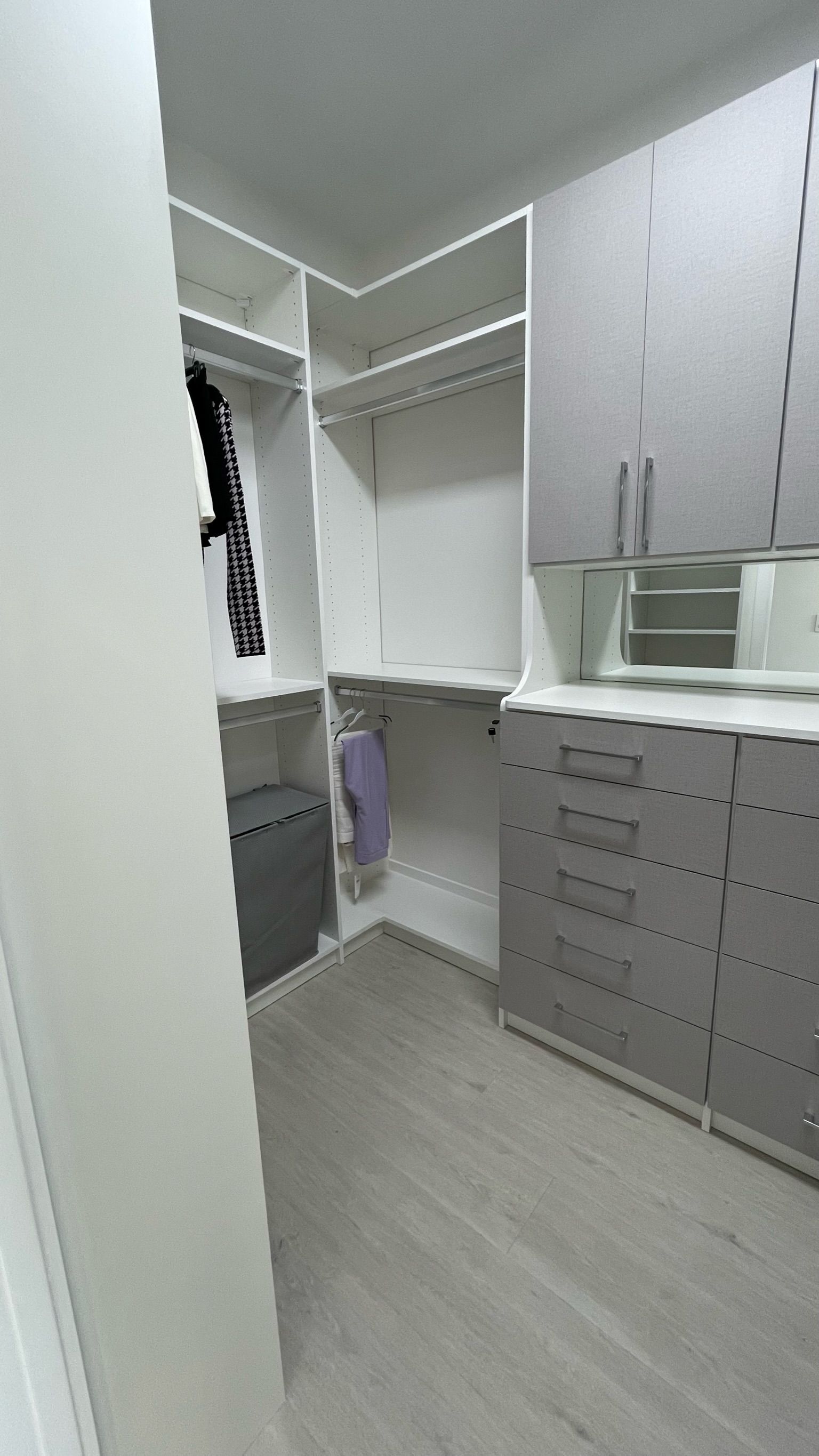 A walk in closet with lots of shelves and drawers and a mirror.