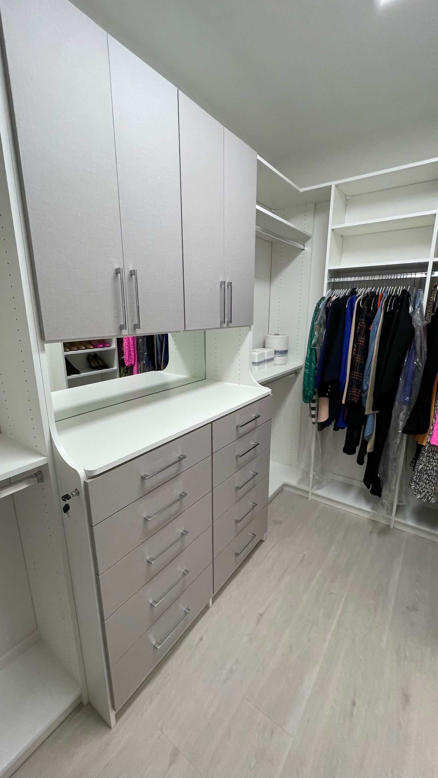 A walk in closet with lots of clothes and drawers.