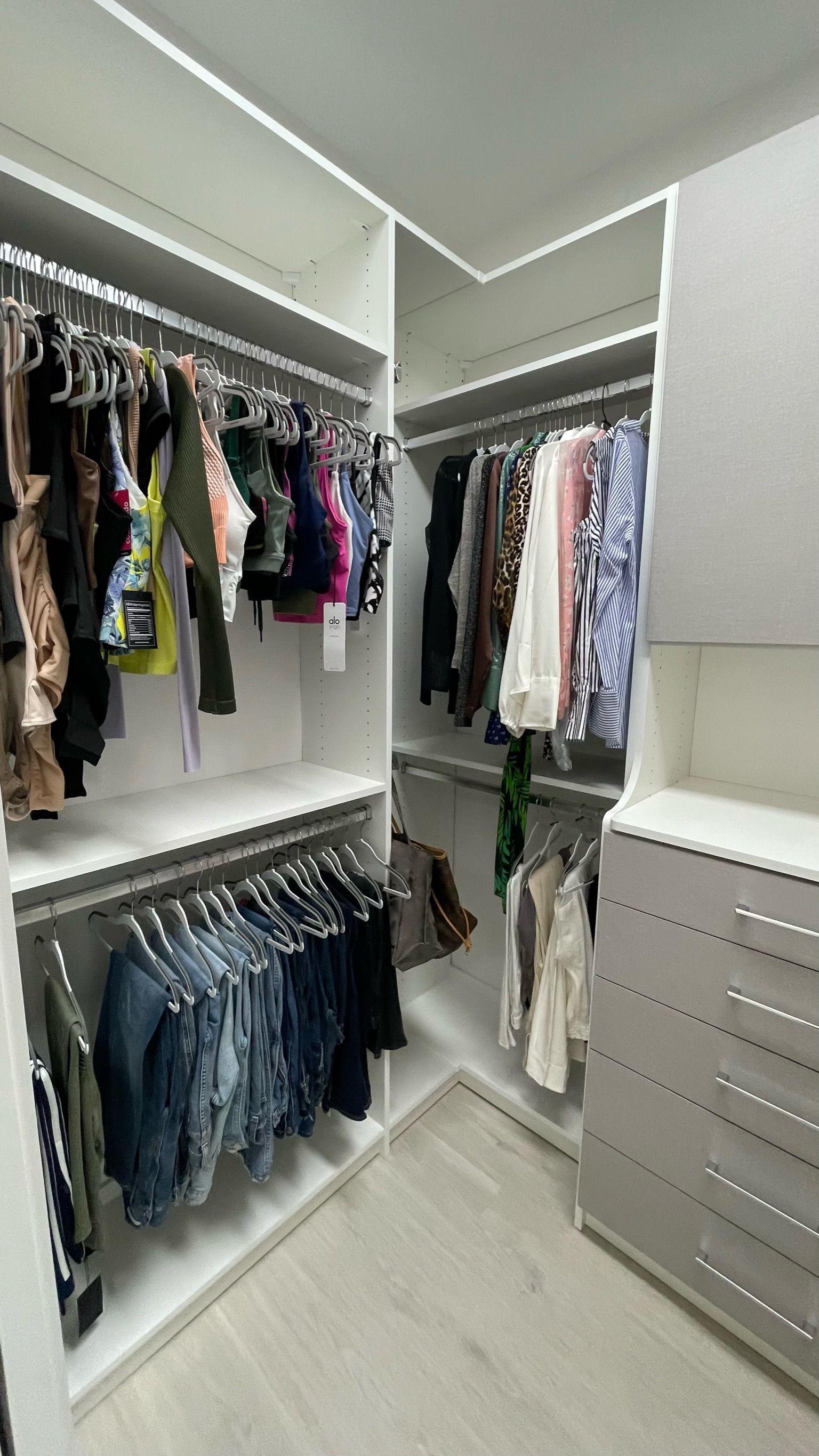 A walk in closet filled with lots of clothes and a dresser.