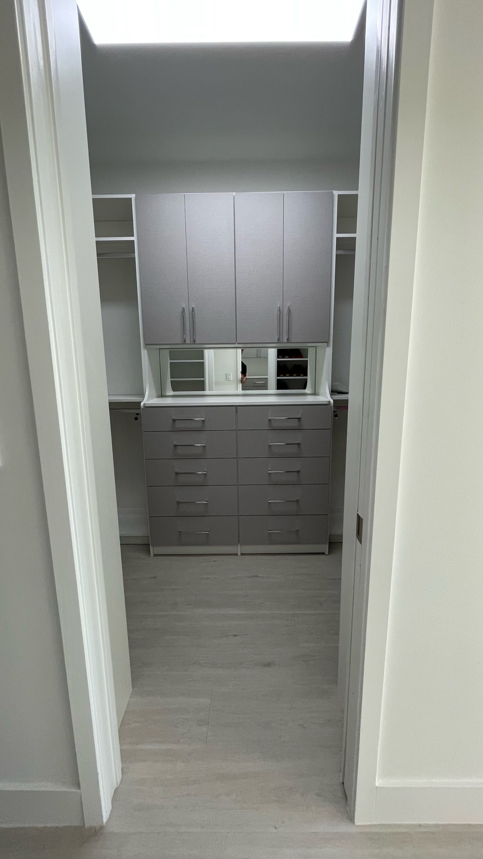 A walk in closet with gray cabinets and drawers in a house.
