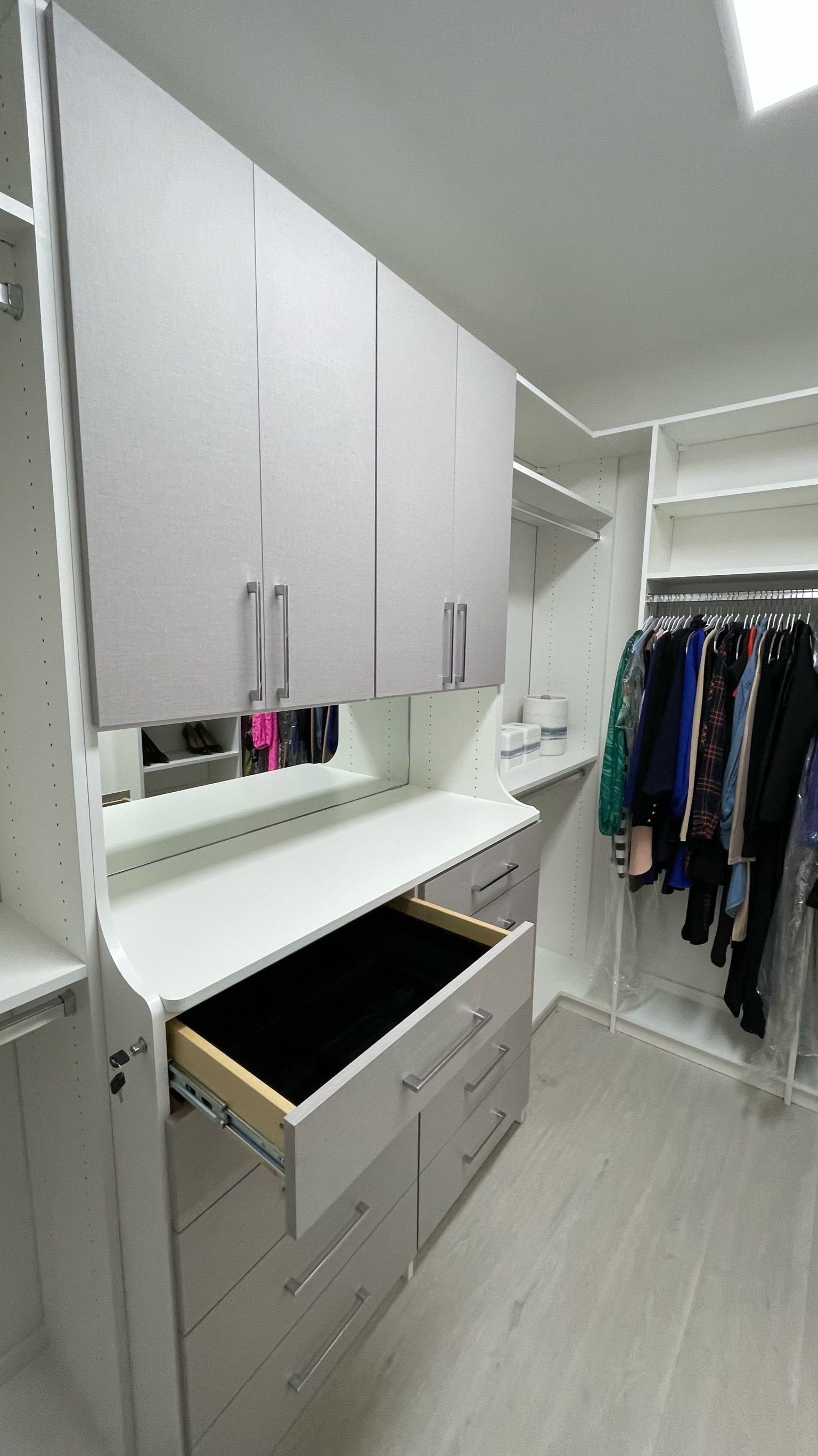 A walk in closet with a drawer open and clothes hanging on the racks.