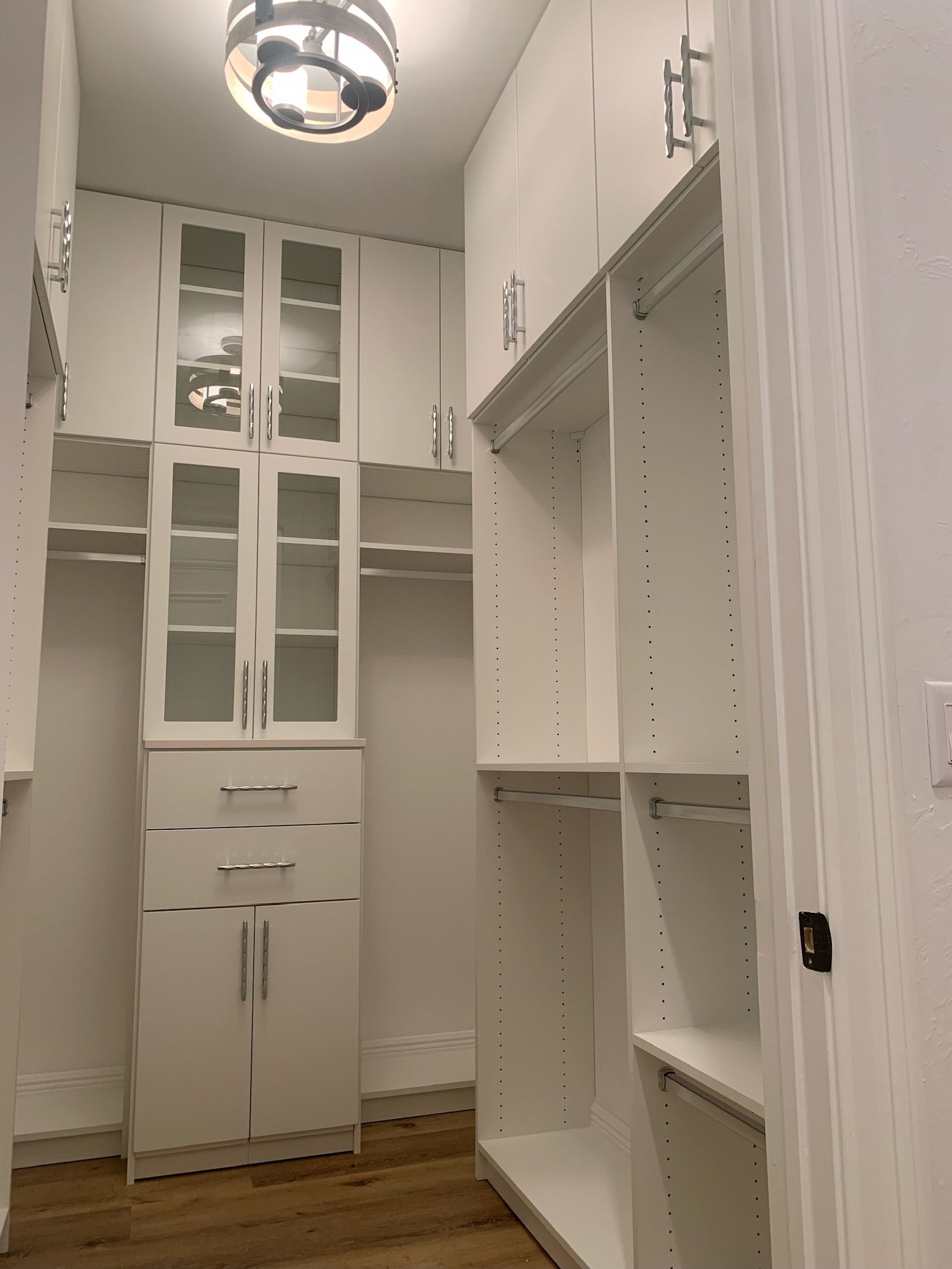 A walk in closet with lots of white cabinets and shelves.