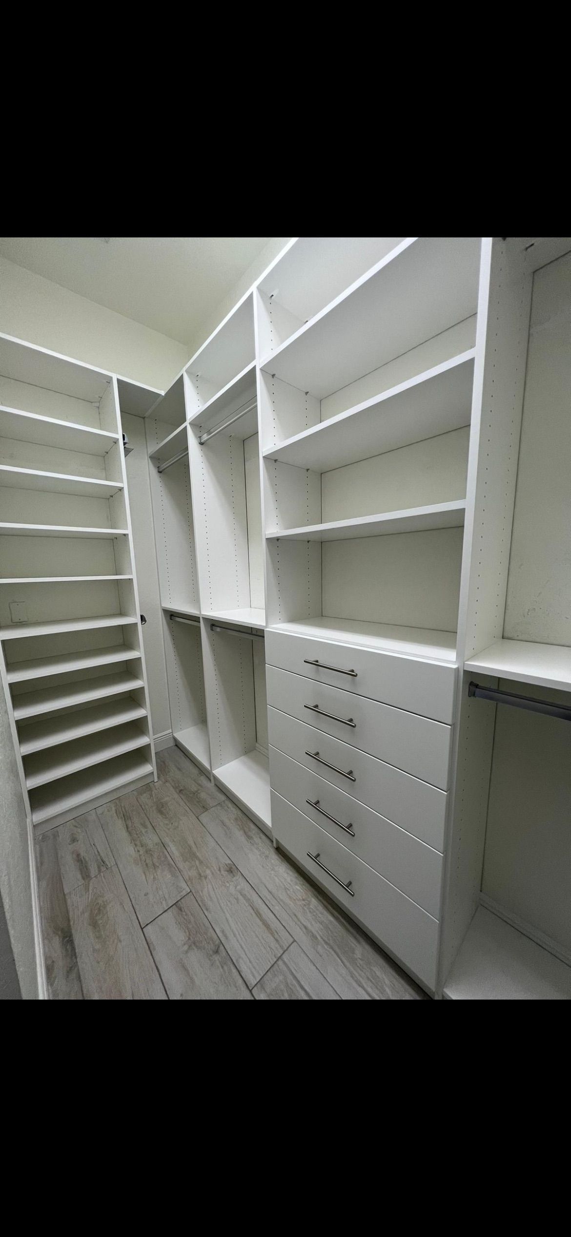 A walk in closet with lots of shelves and drawers.