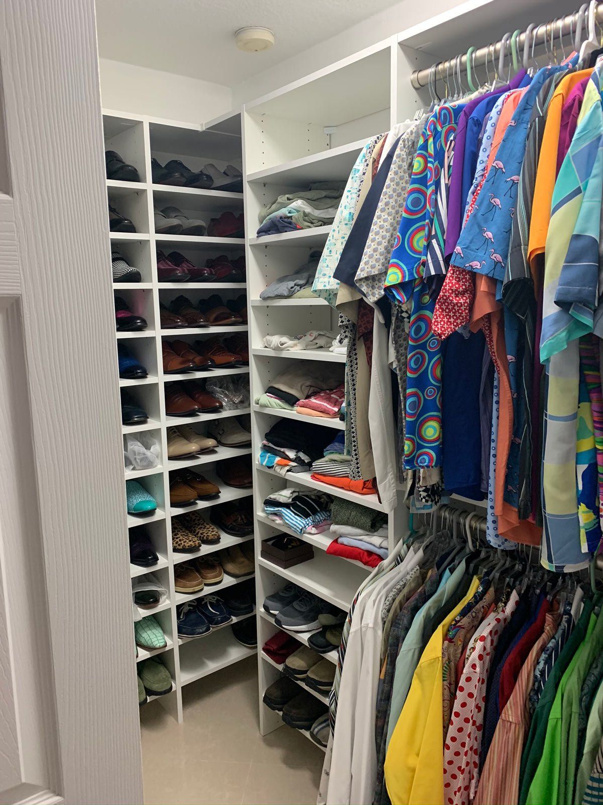 A walk in closet filled with lots of clothes and shoes.