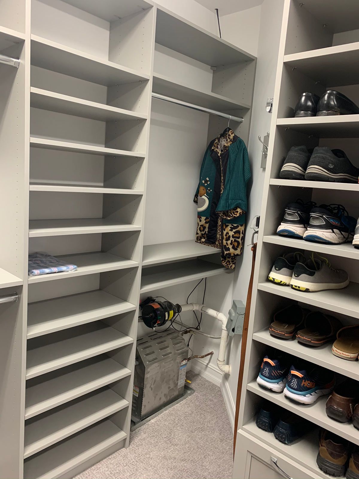 A walk in closet with lots of shelves and shoes.