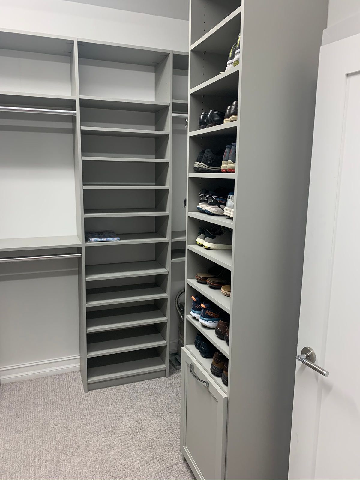 A walk in closet with lots of shelves and a trash can.