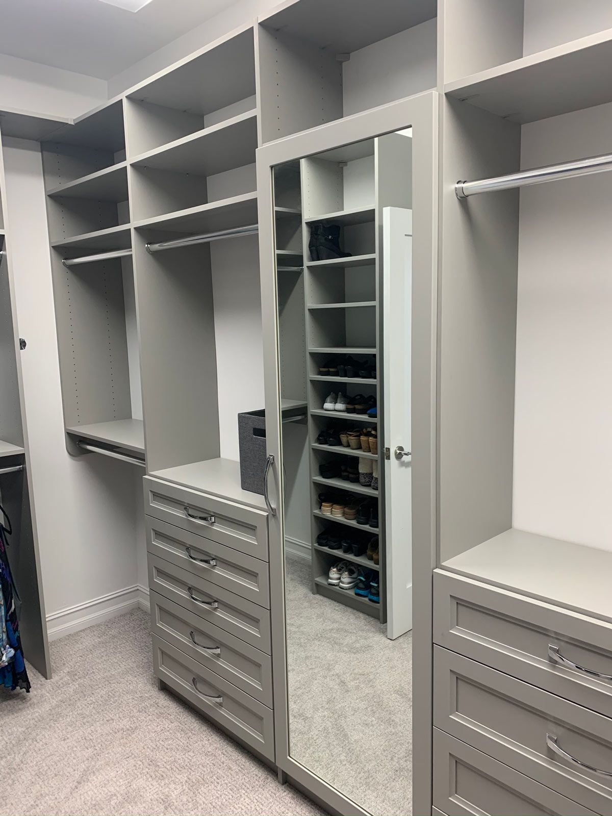 A walk in closet with lots of shelves and drawers and a mirror.