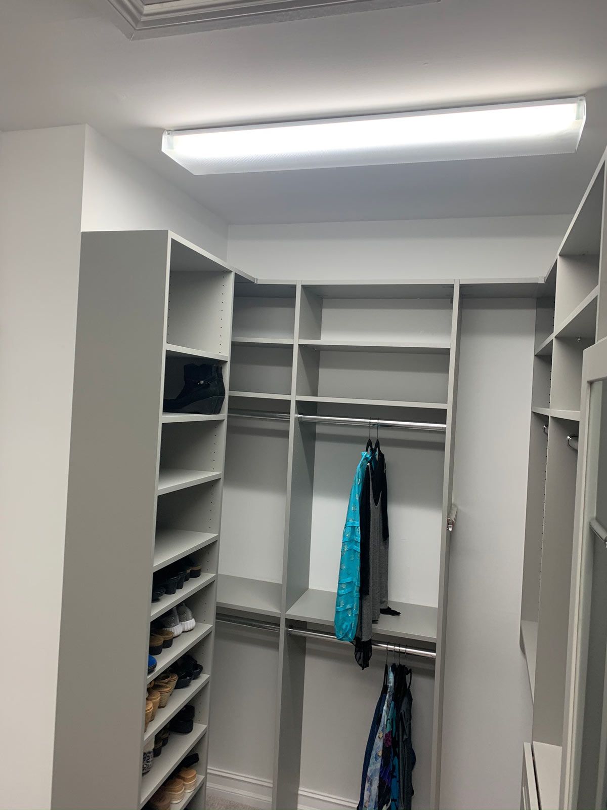 A walk in closet with lots of shelves and a light on the ceiling.