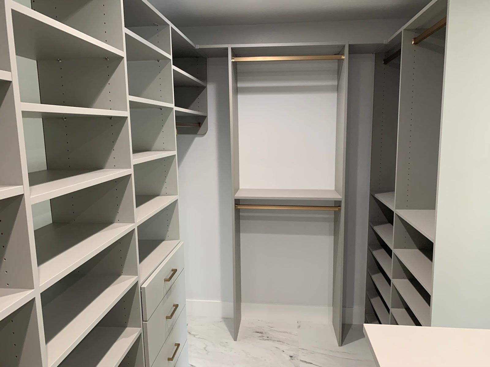 A walk in closet with lots of shelves and drawers