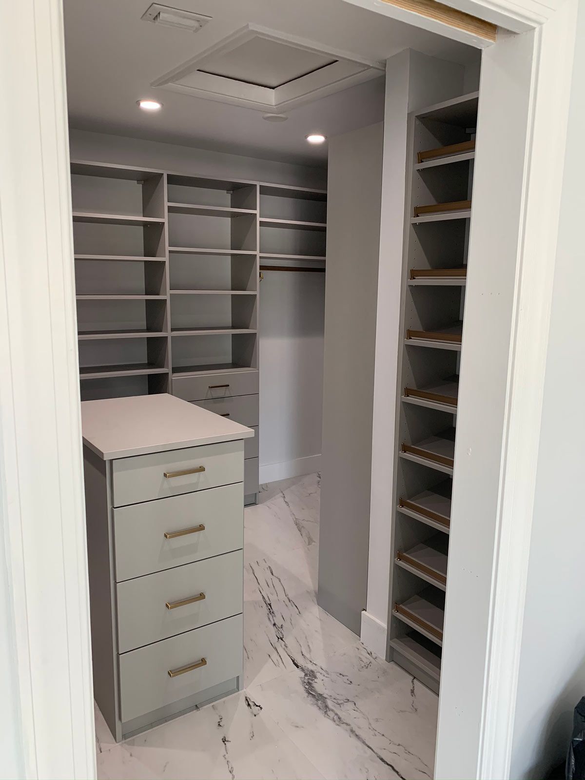 A walk in closet with lots of shelves and drawers.