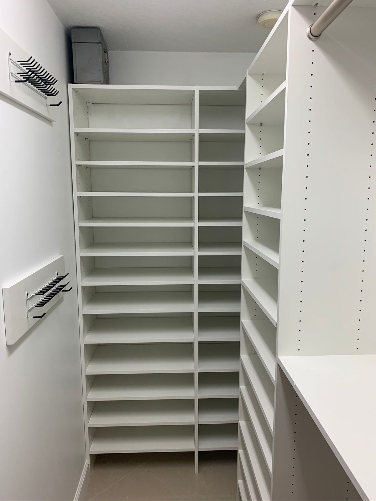 A walk in closet with lots of shelves and hooks.