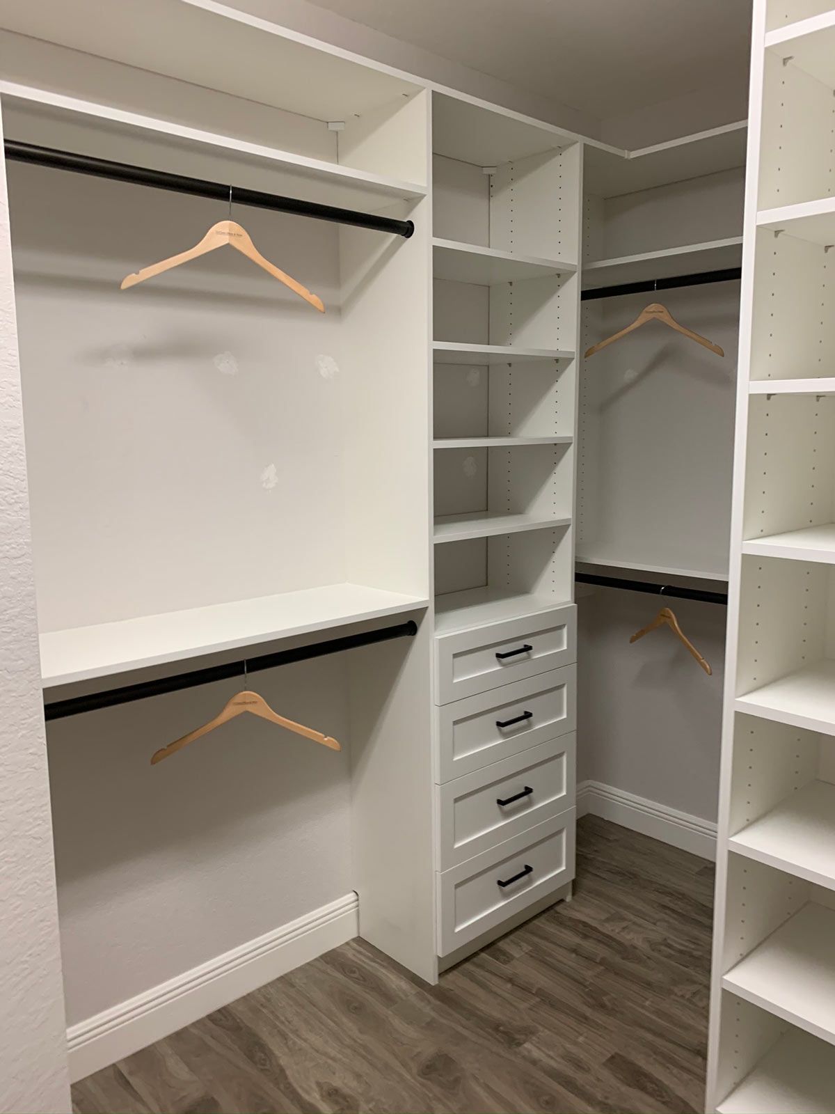 A walk in closet with lots of shelves and clothes hangers.