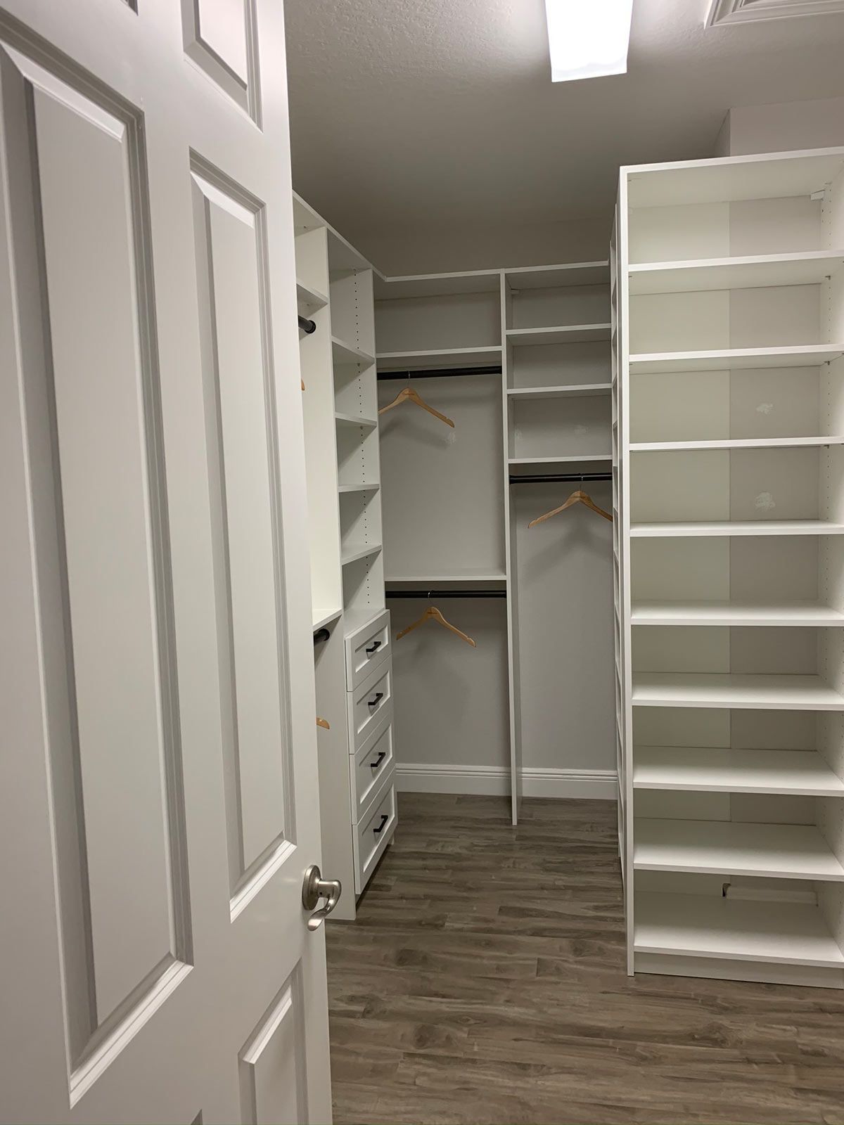 A walk in closet with lots of shelves and drawers.