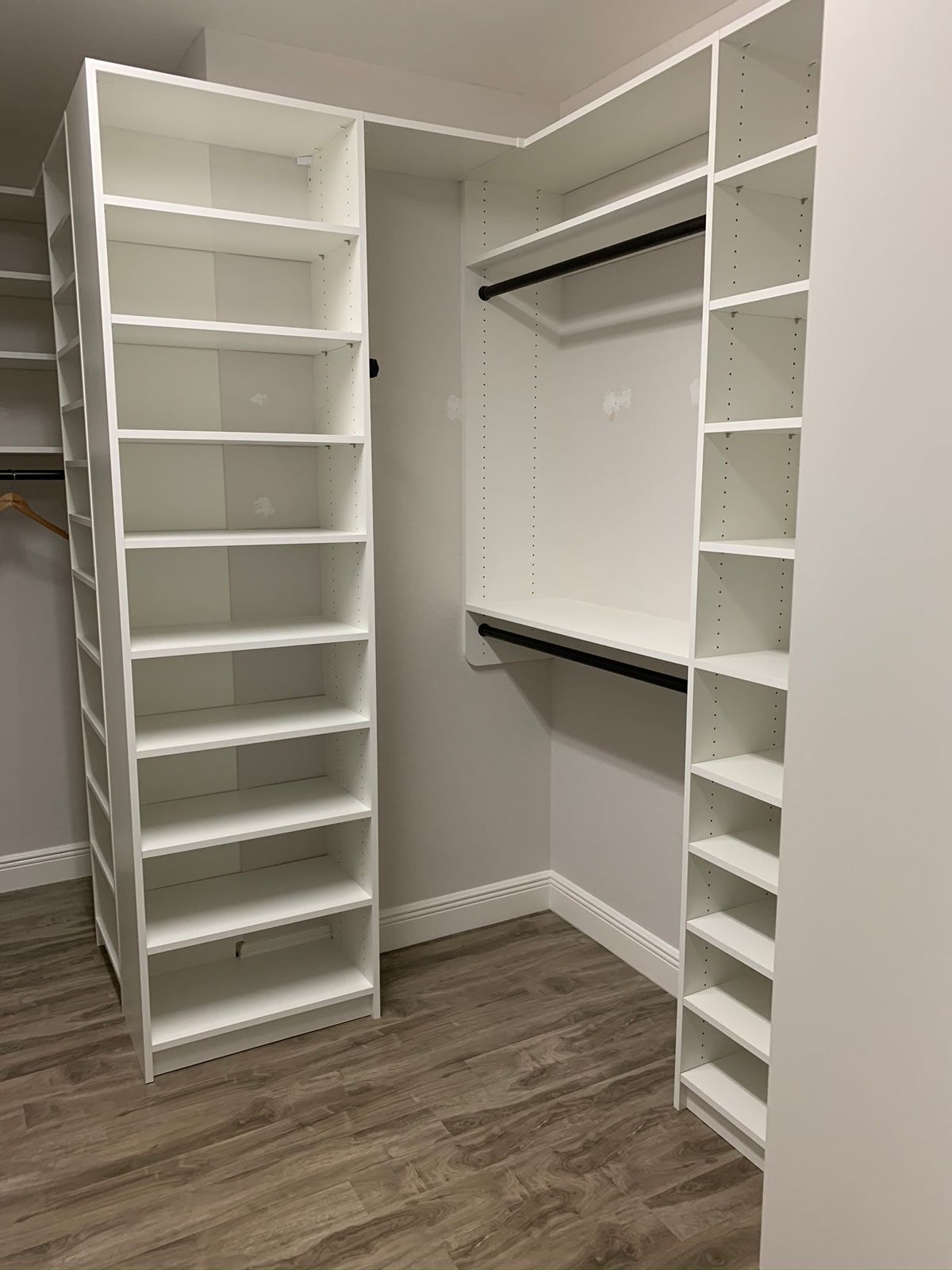 A walk in closet with lots of shelves and a wooden floor.