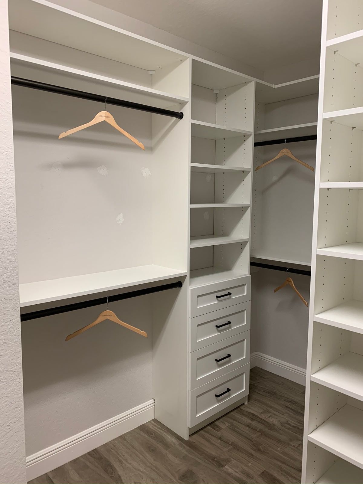 A walk in closet with lots of shelves and clothes hangers.