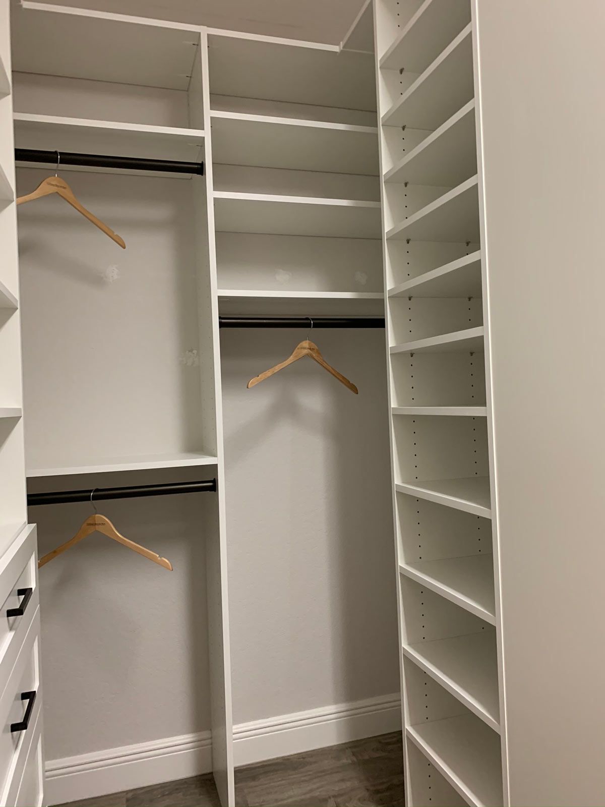 A walk in closet with lots of shelves and clothes hangers.