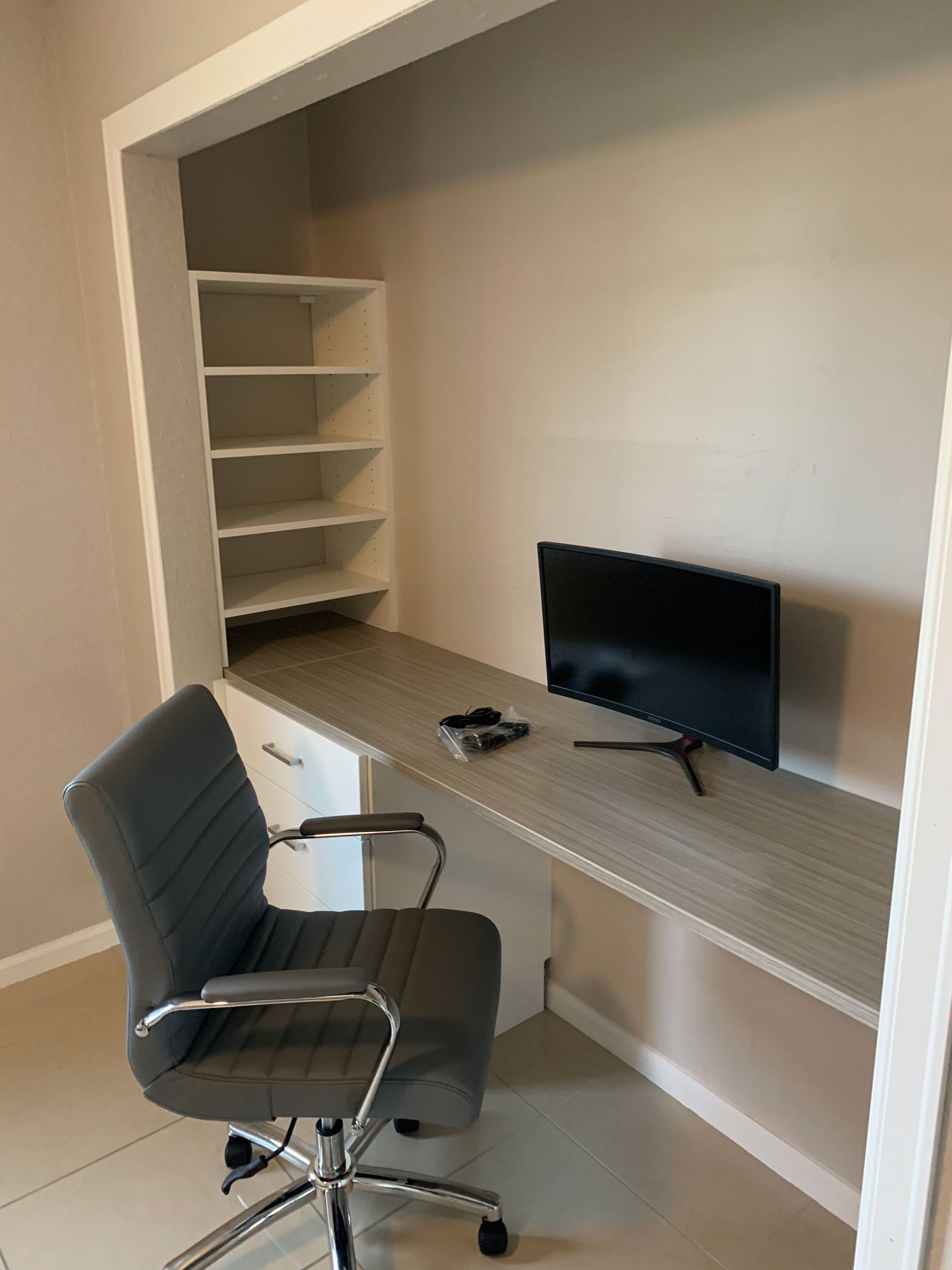 There is a desk with a chair and a television on it.