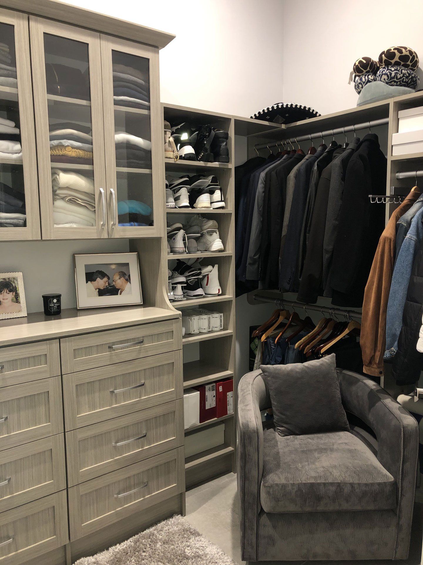 A walk in closet with lots of clothes and a chair.