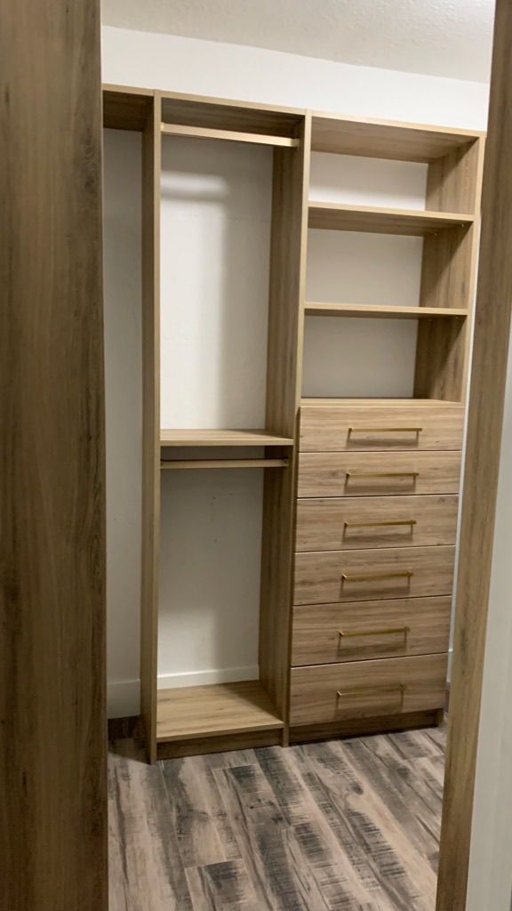 A walk in closet with wooden shelves and drawers in a bedroom.