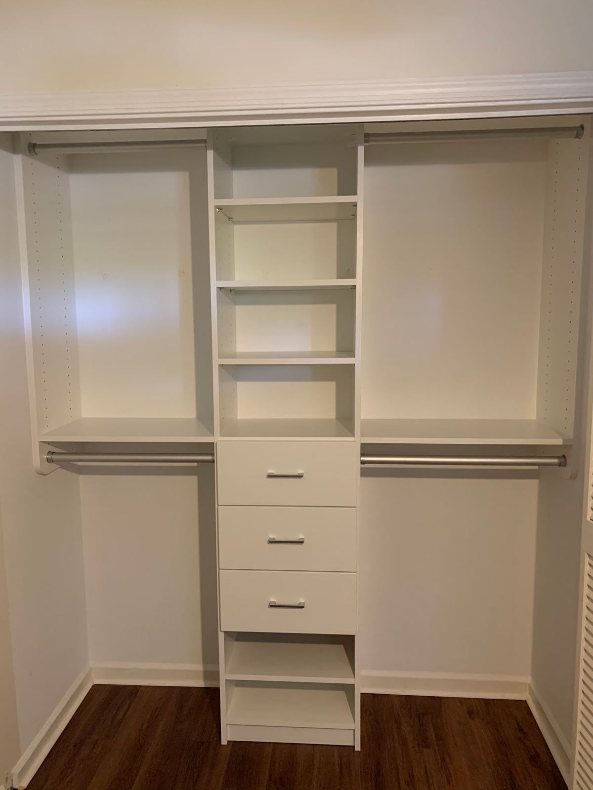 A walk in closet with white shelves and drawers in a bedroom.