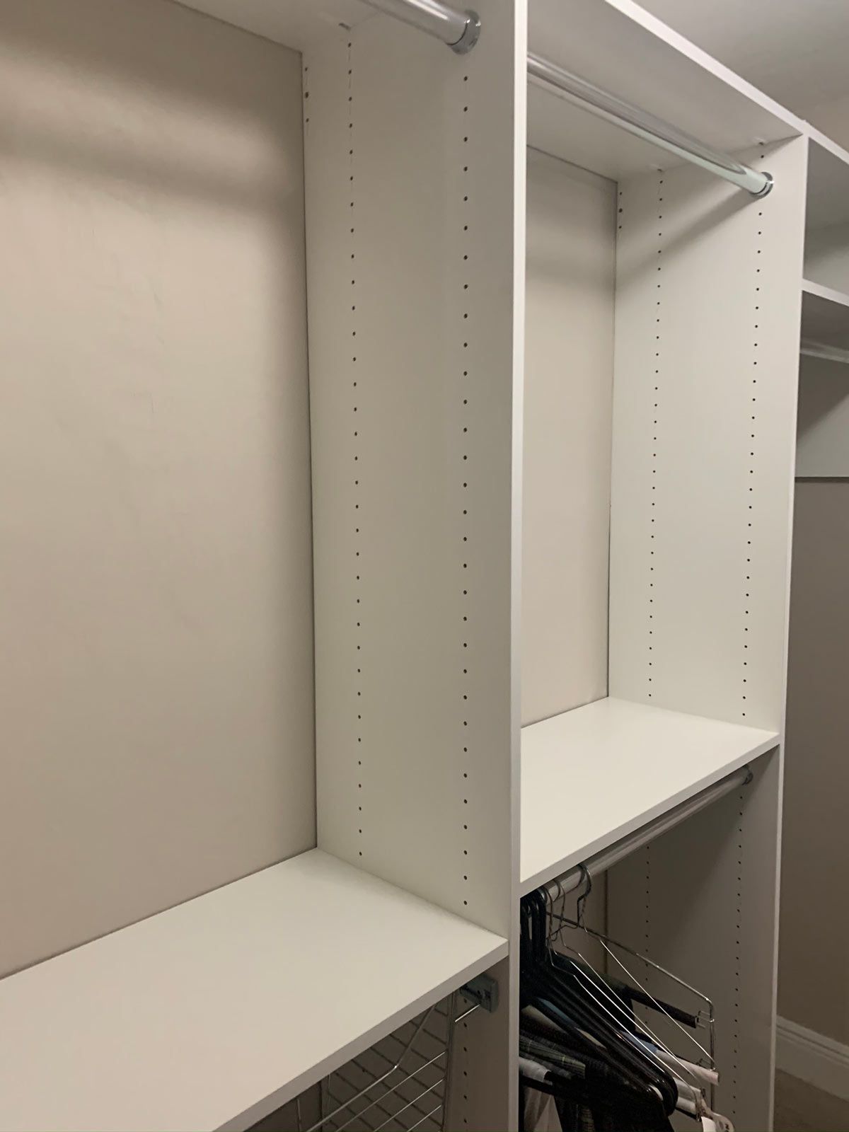 A walk in closet with white shelves and hangers.