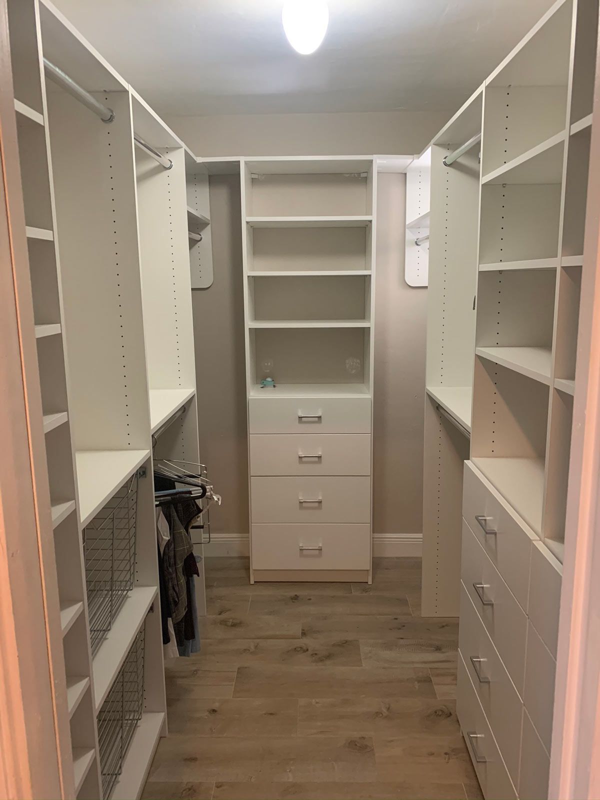A walk in closet with lots of shelves and drawers.