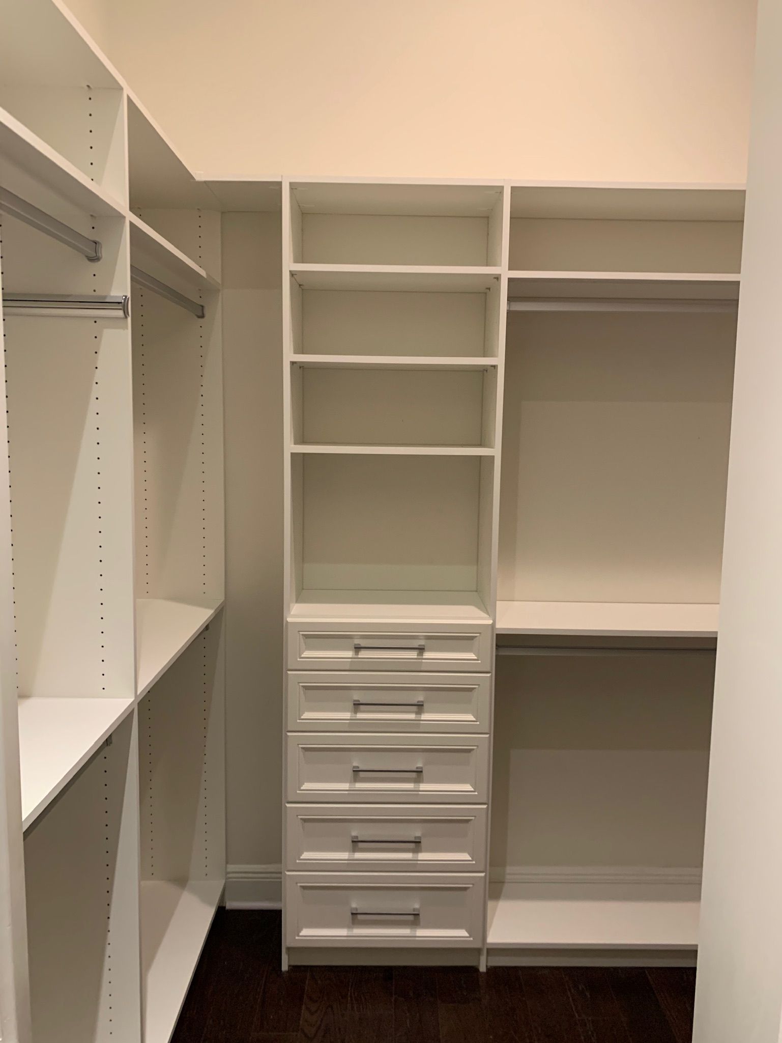 A walk in closet with lots of shelves and drawers.