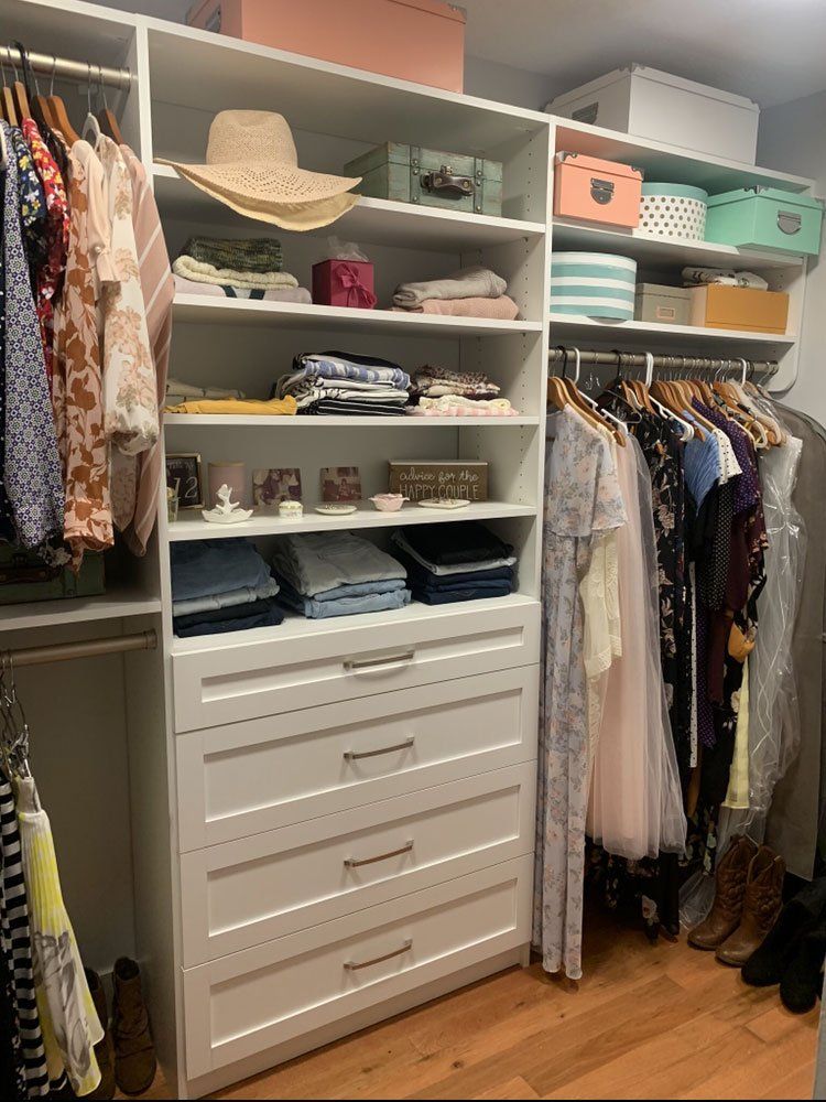 A walk in closet filled with lots of clothes and a dresser.