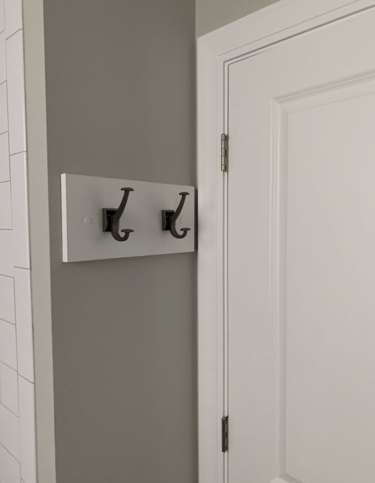 There are two hooks on the wall next to a door.