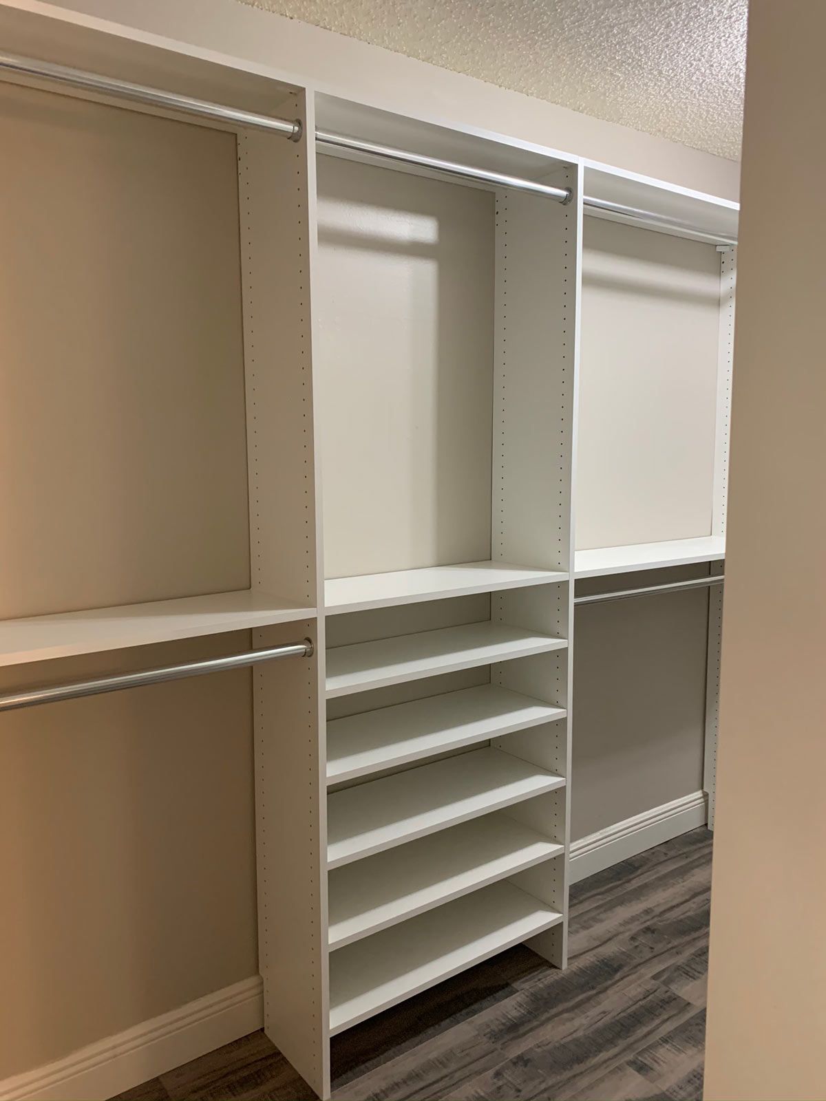 A walk in closet with lots of shelves and clothes racks.