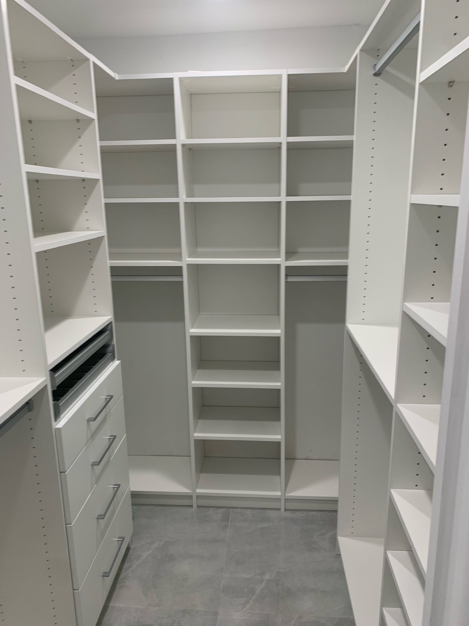 A walk in closet with lots of shelves and drawers.