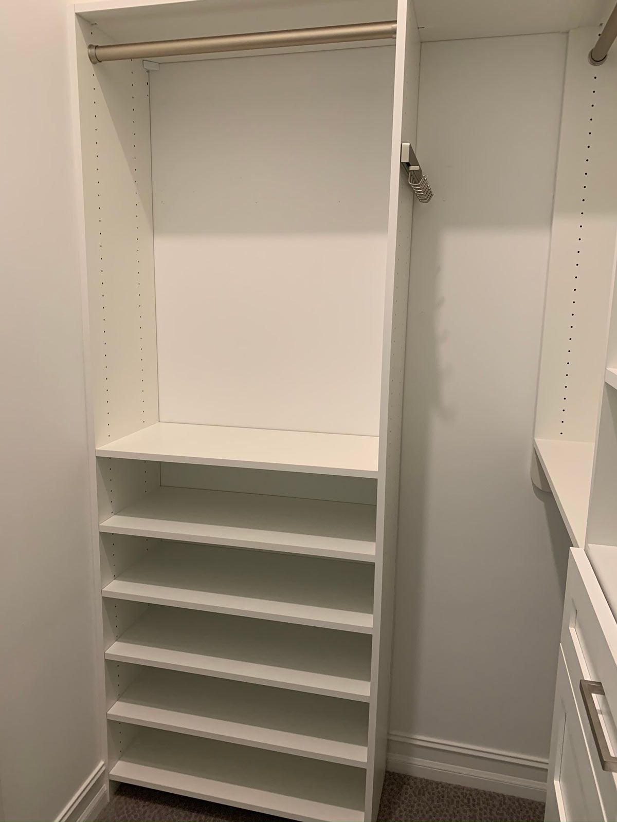 A white closet with lots of shelves and a hanger.