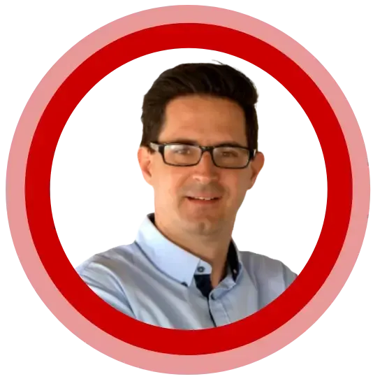 Man with glasses smiling, in a light blue button-down shirt, within a red and pink circular border.