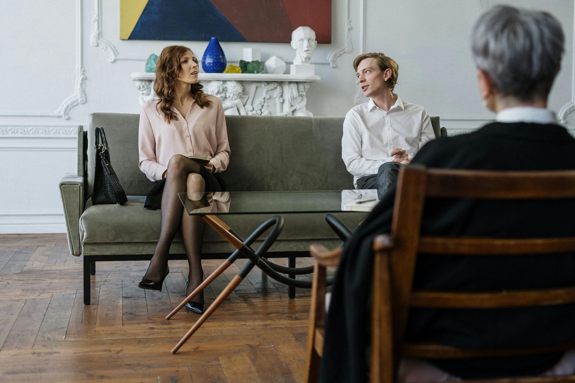 Couple sitting on a sofa in a counseling session, facing the therapist.