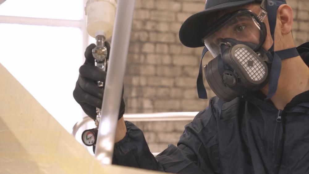 A Man Wearing a Gas Mask and Goggles is Working on a Piece of Metal — Alamo Powder Coaters in Nowra, NSW