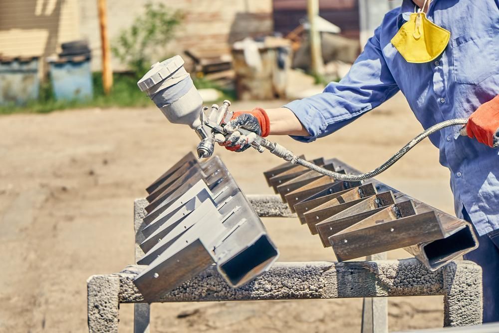 A Man is Spraying Paint on a Piece of Metal — Alamo Powder Coaters in Bowral, NSW
