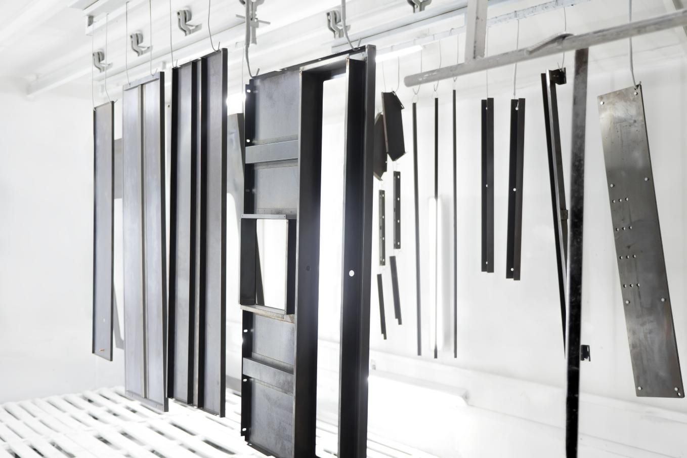 A Room With a Lot of Pieces of Metal Hanging From the Ceiling — Alamo Powder Coaters in Mittagong, NSW