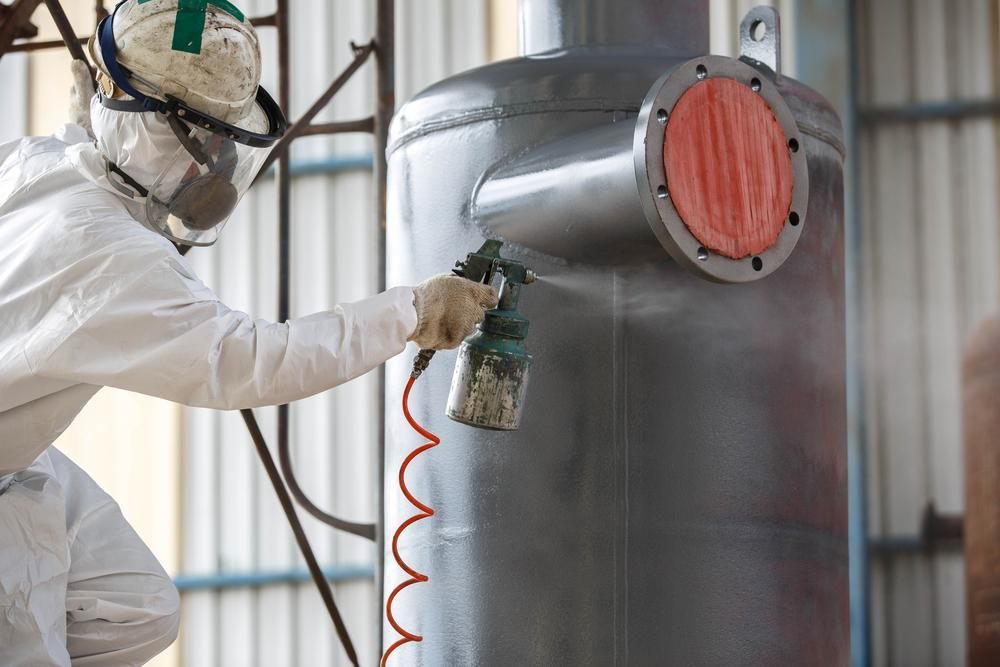 A Man in a Protective Suit is Spray Painting a Metal Object — Alamo Powder Coaters in Mittagong, NSW