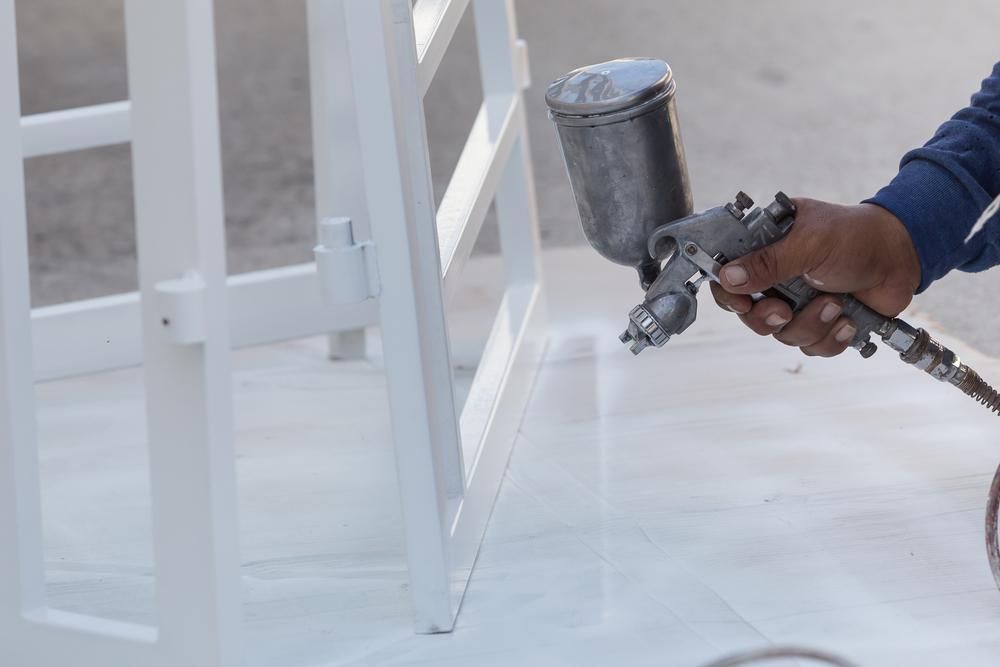 A Man is Spray Painting a Metal — Alamo Powder Coaters in Moss Vale, NSW